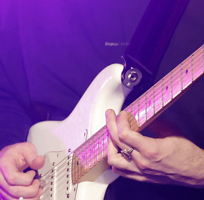 Person playing guitar with auto lock strap